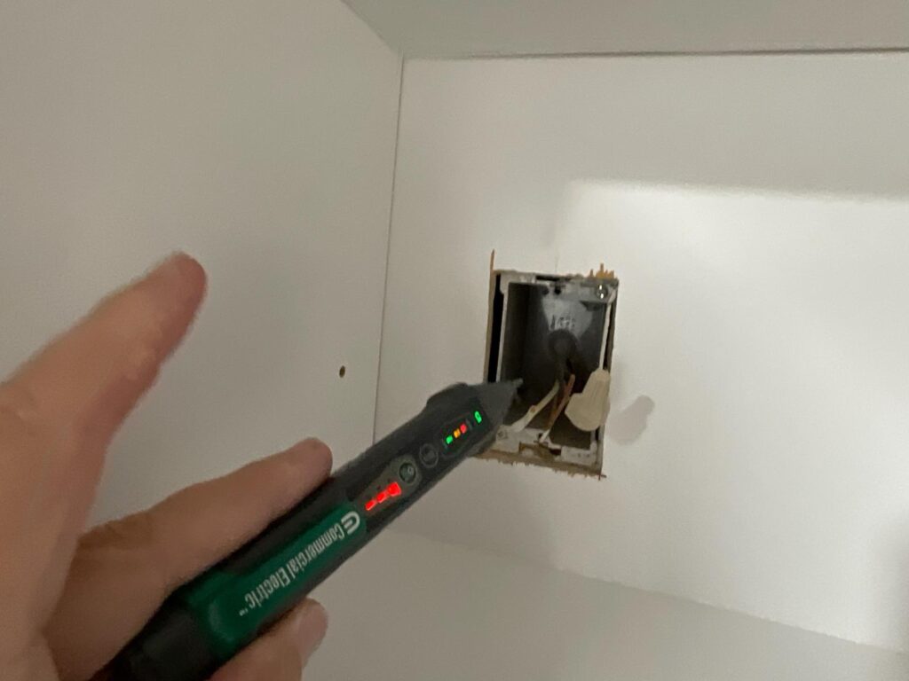 Non-contact voltage tester checking exposed electrical wiring during a home inspection