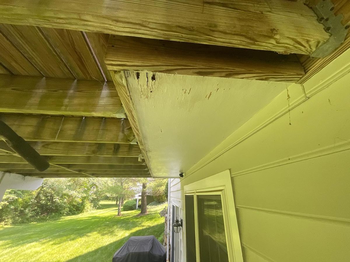 Underside of a deck framed off the cantilevered portion of a house with deterioration at the band