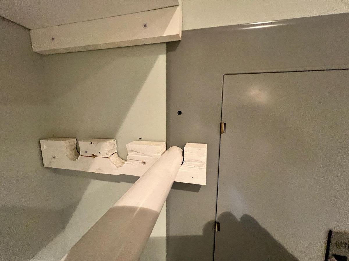 An electrical distribution panel with a closet rod bolted across the front of it