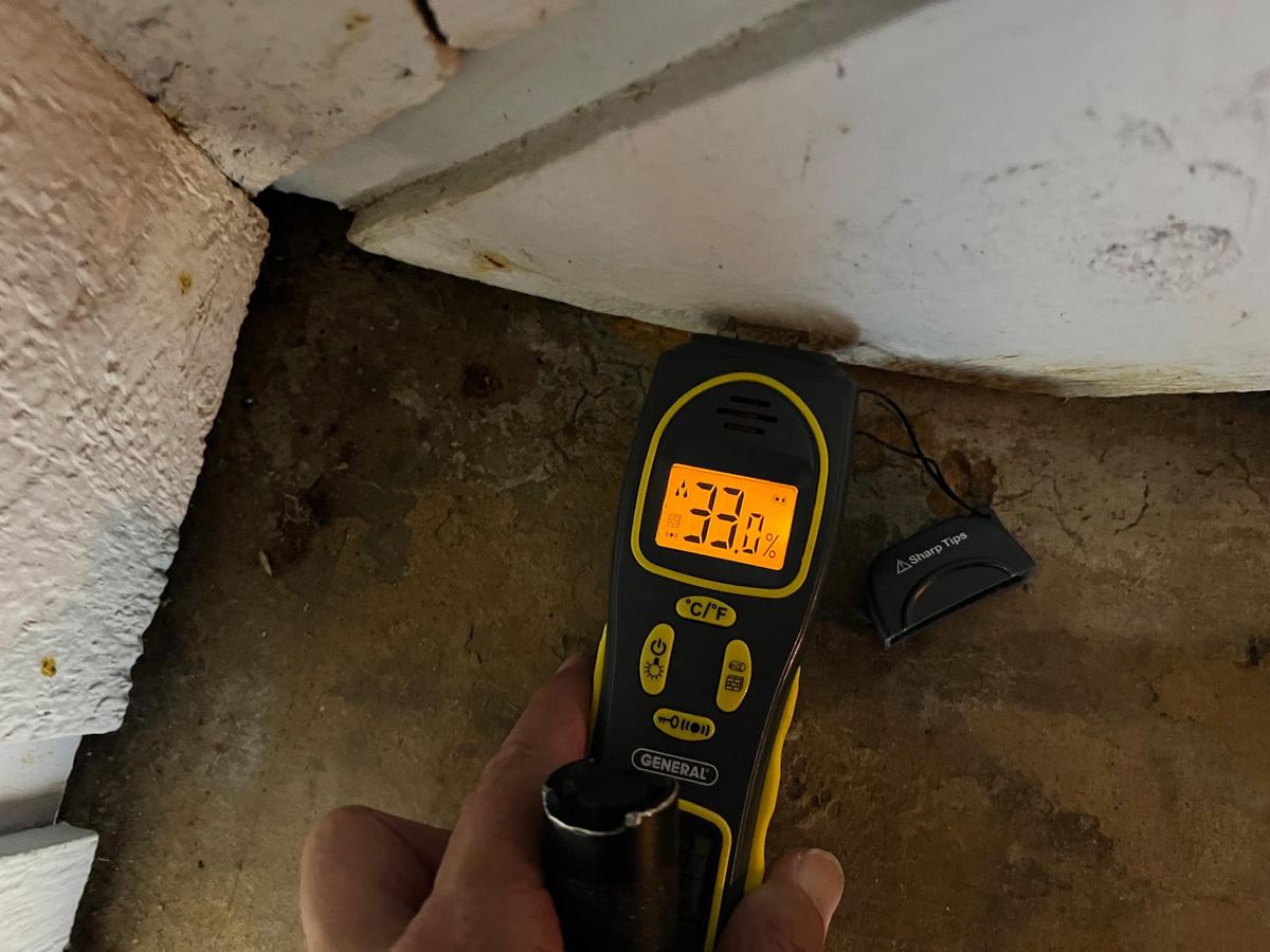 Close-up of a pin-type moisture meter reading taken on a damp interior surface during an inspection