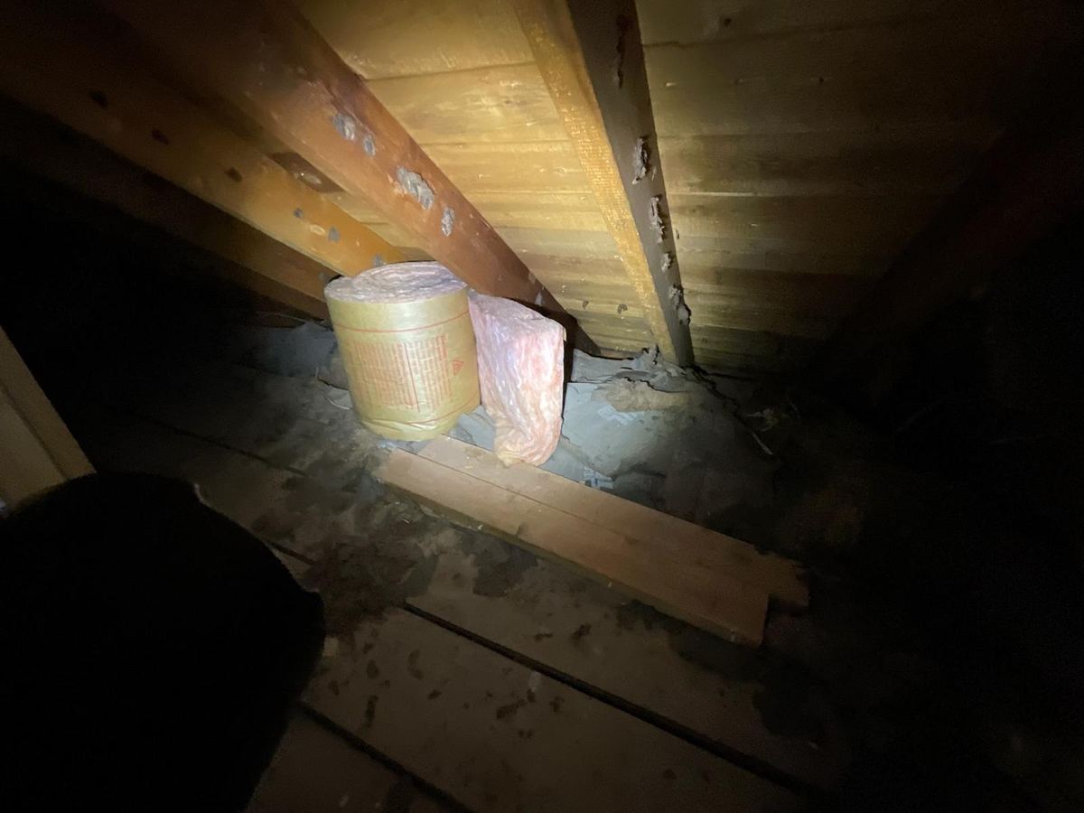 Attic with a roll of insulation still bagged and never laid out across the joists