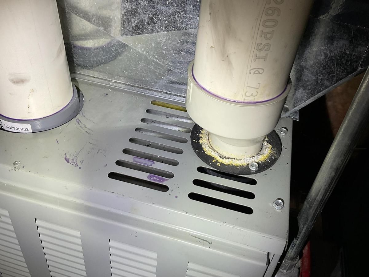 White and yellow powdery crust built up around the PVC exhaust collar on top of a high efficiency furnace